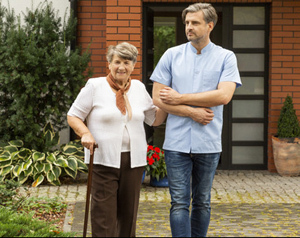 Bildinhalt: ein junger Mann stützt eine ältere Frau beim Gehen